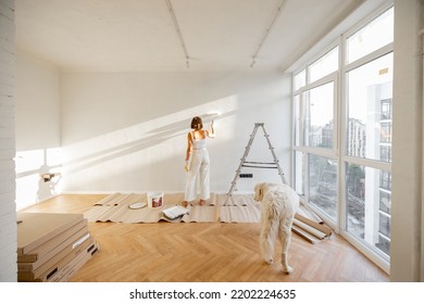 Woman with her dog paints the wall in white color, making repairment in newly purchased apartment. Repair and house renovation concept - Powered by Shutterstock