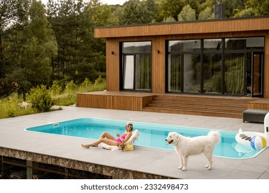 Woman with her dog resting at luxury wooden house with a swimming pool, wide view on property - Powered by Shutterstock