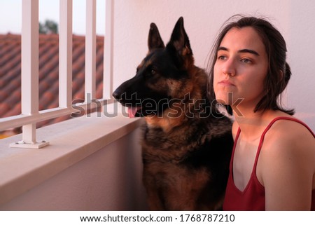 A woman and her dog watching the sunset in the balcony while social distancing