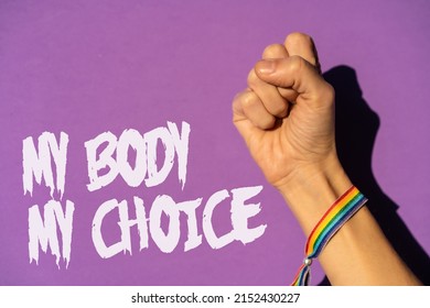 A woman with her fist raised and a text in favor of the legalization of abortion. Protest not to make abortion illegal in the united states, pro-choice, pro-life, on a purple background