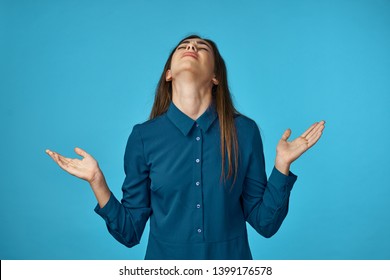 A woman with her hands up tilted her head back against a blue background              