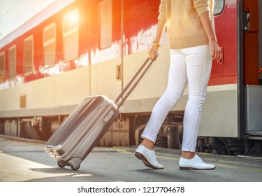 Woman With Her Luggage Go Near The Red Train On The Peron Os Rail Station Under Sun Light At Sunny Day.