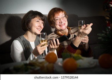 Woman And Her Mother On Christmas Eve, Watching TV At Home Together