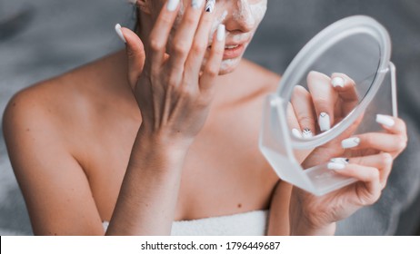 Woman in her room making facial mask holding mirror in his hands. Morning skin care routine. Stay at home while quarantined to avoid coronavirus. - Powered by Shutterstock