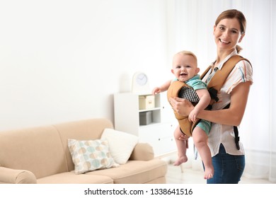 Woman With Her Son In Baby Carrier At Home. Space For Text