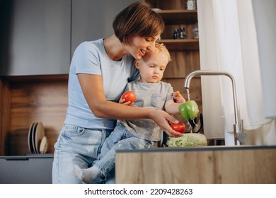 Woman with her son washing vegetables in the kitchen sink - Powered by Shutterstock