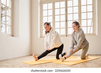 Woman and her teen daughter stretching legs at the yoga mat at home - Powered by Shutterstock