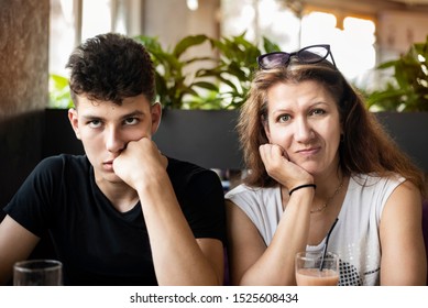 Woman With Her Teenage Son In A Cafe Drink Juice And Try To Understand Each Other - Woman As Mom, Boy As Son. A Boy Shows That He Can Not Listen To His Mother, And Mother Has Emotions Of Happiness