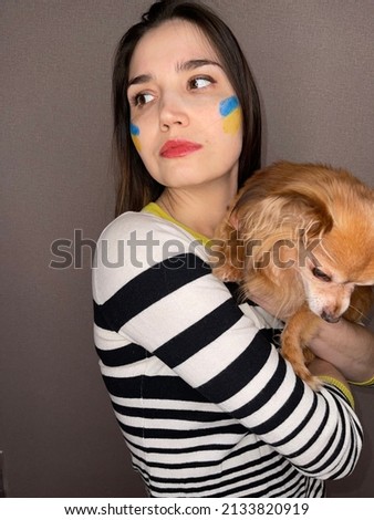Woman in her thirties with dark hair and the flag of Ukraine on her cheek