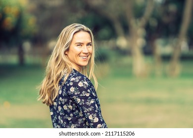 Woman In Her Thirties Turns Smiling At The Camera In A Flowery Shirt