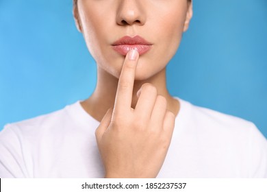 Woman with herpes touching lips on light blue background, closeup - Shutterstock ID 1852237537