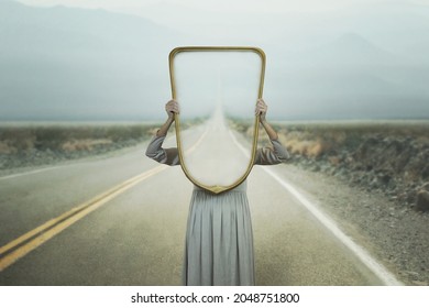the woman hides holding a mirror in front of her face; introspection path concept - Shutterstock ID 2048751800