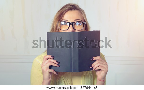グレイの本の後ろに隠れている女性 顔を覆う女性 内緒 本の後ろに眼鏡を隠し カメラの驚きを見つめた女性 教育のコンセプト 顔の式 本を持つ女の子 の写真素材 今すぐ編集