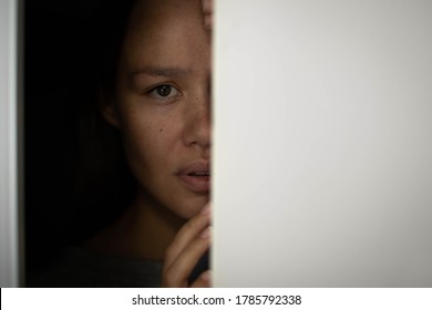 Woman Hiding In The Closet Afraid With Worry In Her Eyes.