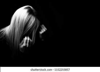 A woman hiding face. Violence against women concept. Black and white studio shot.