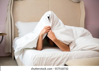Woman hiding under a blanket. Person in bed. No one can find me.