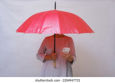 Woman Hiding Under Red Umbrella With Cellular Phone In One Hand