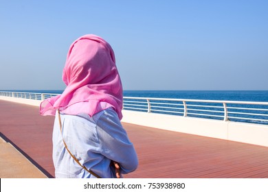 Woman In Hijab Back Standing In Front Of Blue Sea.