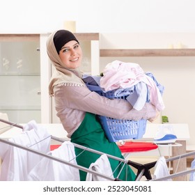 Woman in hijab doing clothing ironing at home - Powered by Shutterstock