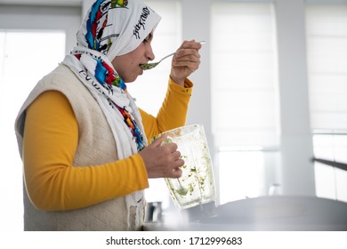 Woman with hijab drinking green smoothie from the blender - Powered by Shutterstock