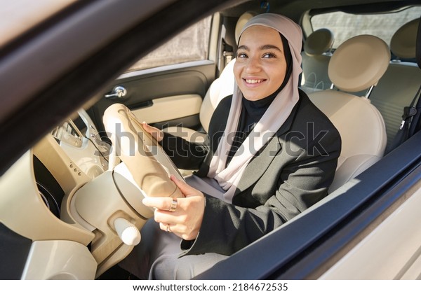 Woman in a hijab is driving a\
car