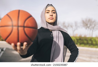 woman with hijab and sportswear and basketball ball - Powered by Shutterstock