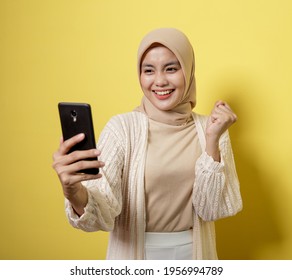 woman hijab with a video calling phone expression isolated on yellow background - Powered by Shutterstock