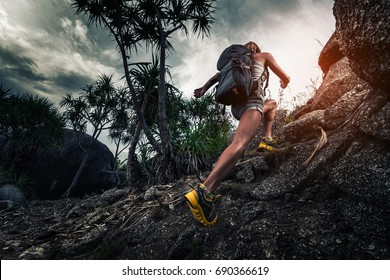 Woman hiker with backpack climbs steep rocky terrain