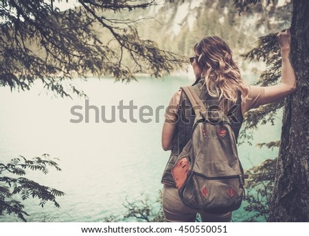 Woman hiker with backpack enjoying amazing mountain lake landscapes.
