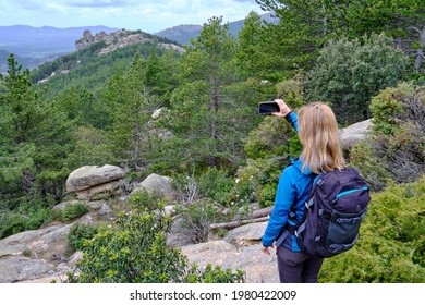 Woman Hiker From Behind Taking Picture Of Landscape With Mobile Phone. Female Trekker Photographing In Nature.