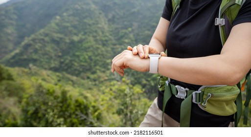 Woman hiker checking on smartwatch on mountain top