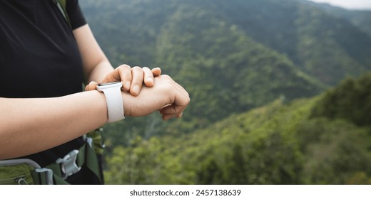 Woman hiker checking on smartwatch on mountain top - Powered by Shutterstock