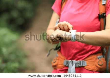 Woman hiker checking on smartwatch on hiking travel  