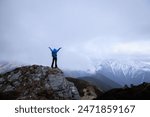 Woman hiker enjoy the view on mountain top cliff edge face the snow capped mountains in tibet