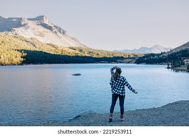 Woman hiker enjoying view of the beautiful lake, view from the back. Yosemite national park, Tioga lake