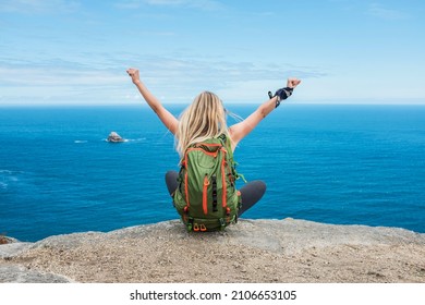 Woman hiker, hiking backpacker traveler camper  on the top of mountain in sunny day under sun light. Beautiful sea landscape view.