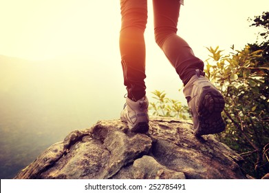 Woman hiker legs on mountain peak rock cliff edge 