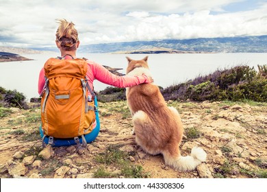 Woman hiker looking at sea with akita inu dog on seaside trail. Recreation and healthy lifestyle outdoors in summer mountains and sea nature. Beautiful inspirational landscape, trekking and activity. - Powered by Shutterstock