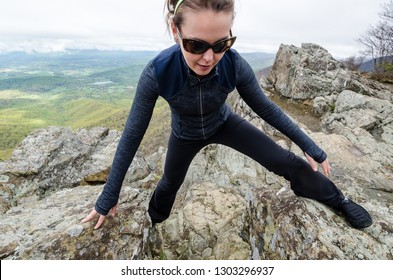 Woman Hiker And Rock Climber Concentrates On Scrambling Up A Steep Section Of Rock Outcroppings In Shenandoah National Park