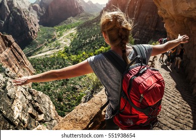 Woman hiker standing with raised hands and watching valley view of Zion National Park, USA