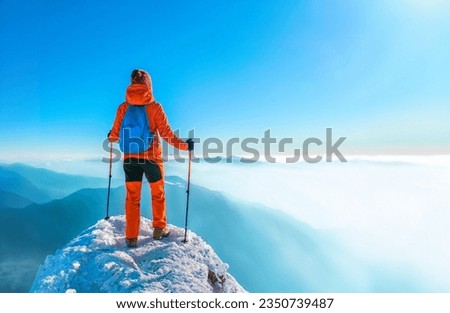 Woman hiker successful on mountain peak summit in winter mountain