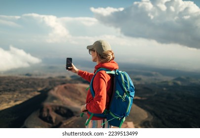 Woman hiker taking photo on slopes of Mt. Etna	