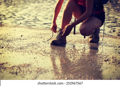 woman hiker tying shoelace on sunrise  beach - Powered by Shutterstock