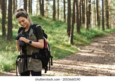 Woman hiker using modern mirrorless camera in green forest