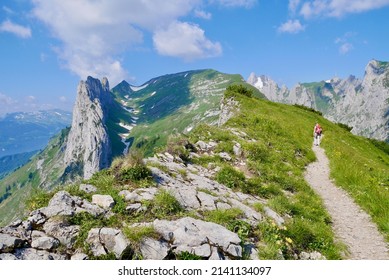 Woman hiking in Alpstein massif, Kreuzberge, Chruezberg in the background. St. Gallen, Switzerland. High quality photo