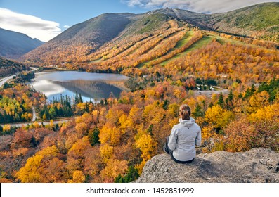 Woman hiking at Artist's Bluff in autumn. View of Echo Lake. Fall colours in Franconia Notch State Park. White Mountain National Forest, New Hampshire, USA
