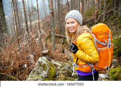 Woman Hiking In Autumn Forest In Mountains. Recreation And Healthy Lifestyle Outdoors In Nature. Beauty Blond Looking At Camera Smiling.