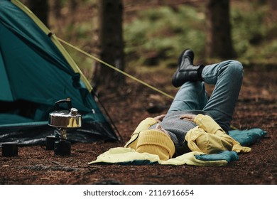 Woman In Hiking Gear Lying On Her Sleeping Bag At Her Campsite After A Night Camping In The Woods