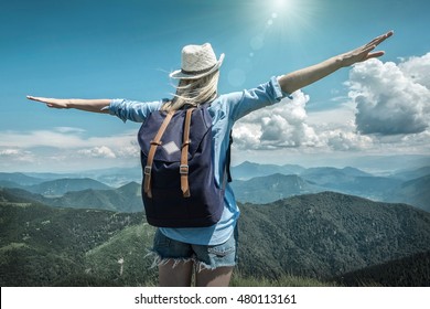 Woman hiking in mountains at sunny day time.