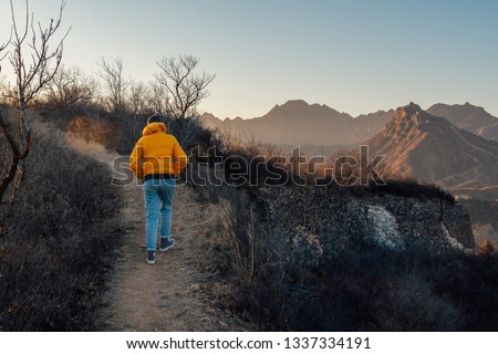 Woman hiking on mountain path into the wild at sunset or sunrise above mountains- traveling adventure- lifestyle- outdoor activity and nature adventure concept